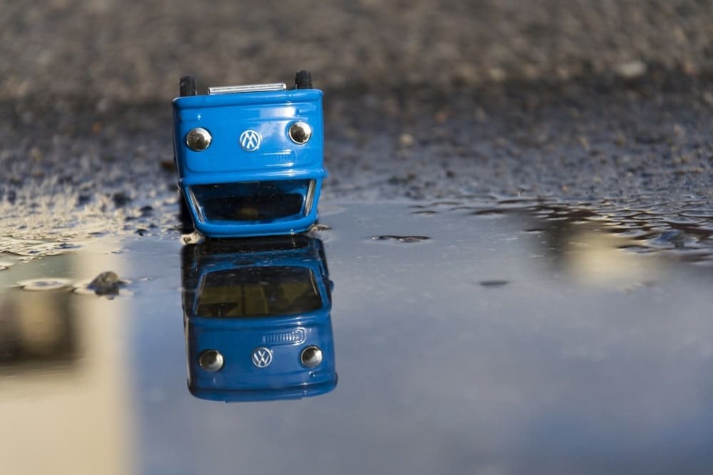 model blue VW van upside down in a puddle